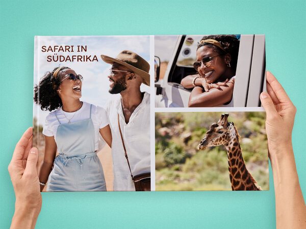 Zwei Hände halten ein großes A3-Fotobuch im Querformat. Auf dem Cover ist eine Collage mit Bildern einer Safari abgebildet.