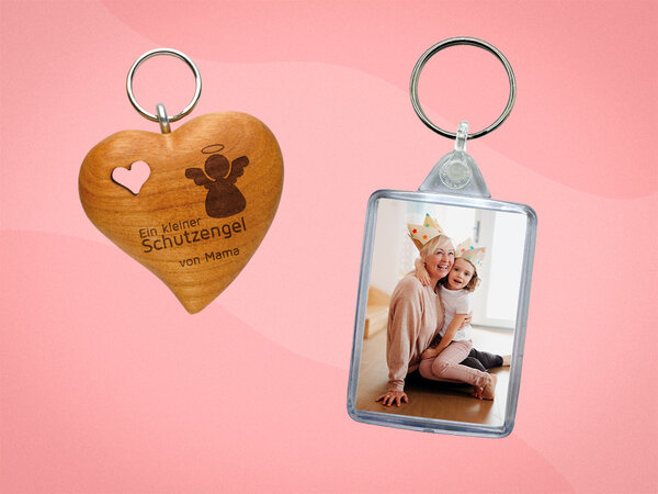 Herzförmiger Holzanhänger mit ausgestanztem Herz und persönlicher Gravur. Daneben ein Schlüsselanhänger aus Acryl mit Foto.
