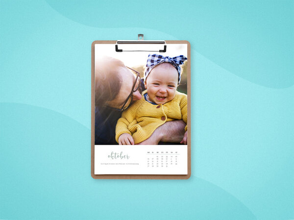 Wandkalender mit Klemmbrett und weißem Design mit geschwungener Schrift, mit einem Foto von Baby mit Papa.